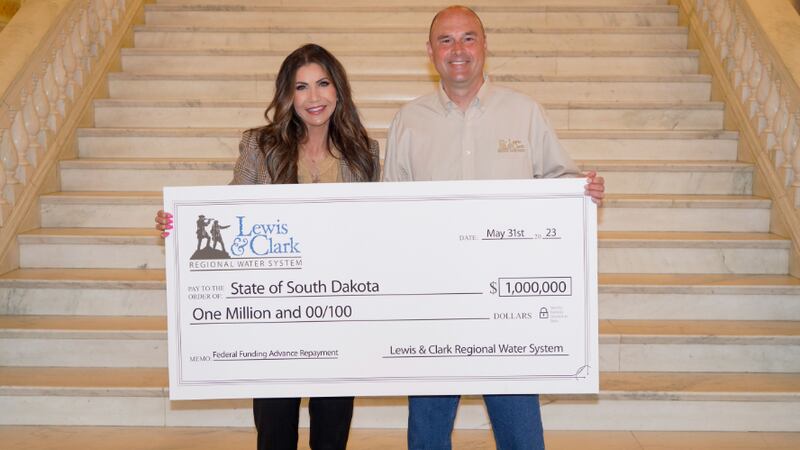 Larson and Noem with a ceremonial check before actual check was hand delivered.